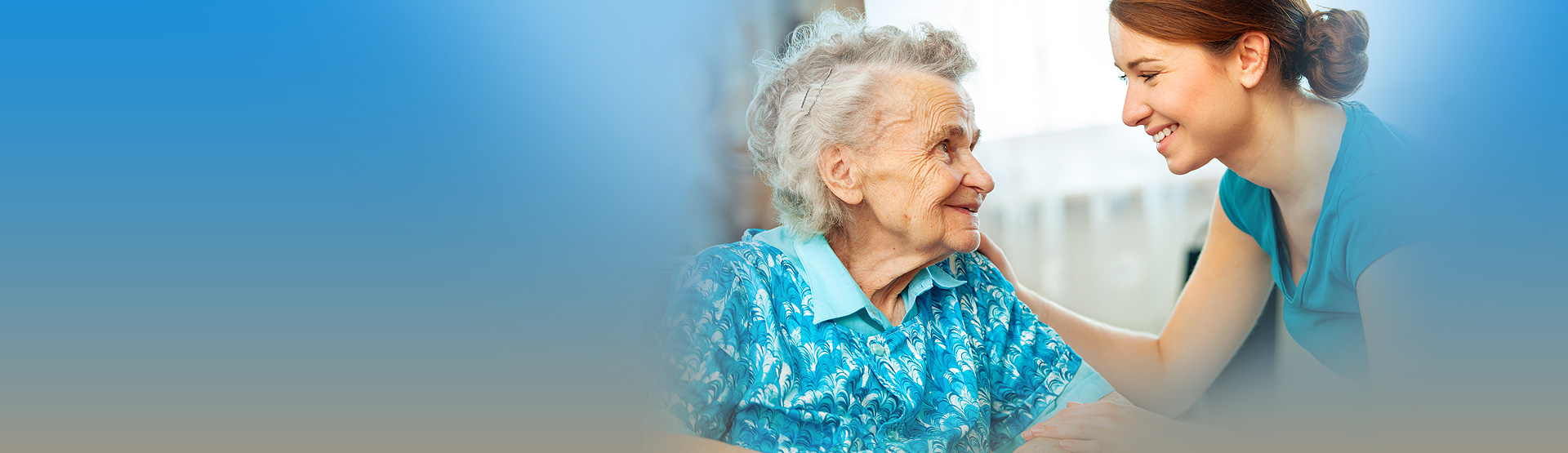 Uśmiechnięta opiekunka trzymająca za rękę seniorkę — moment bliskości i zaufania